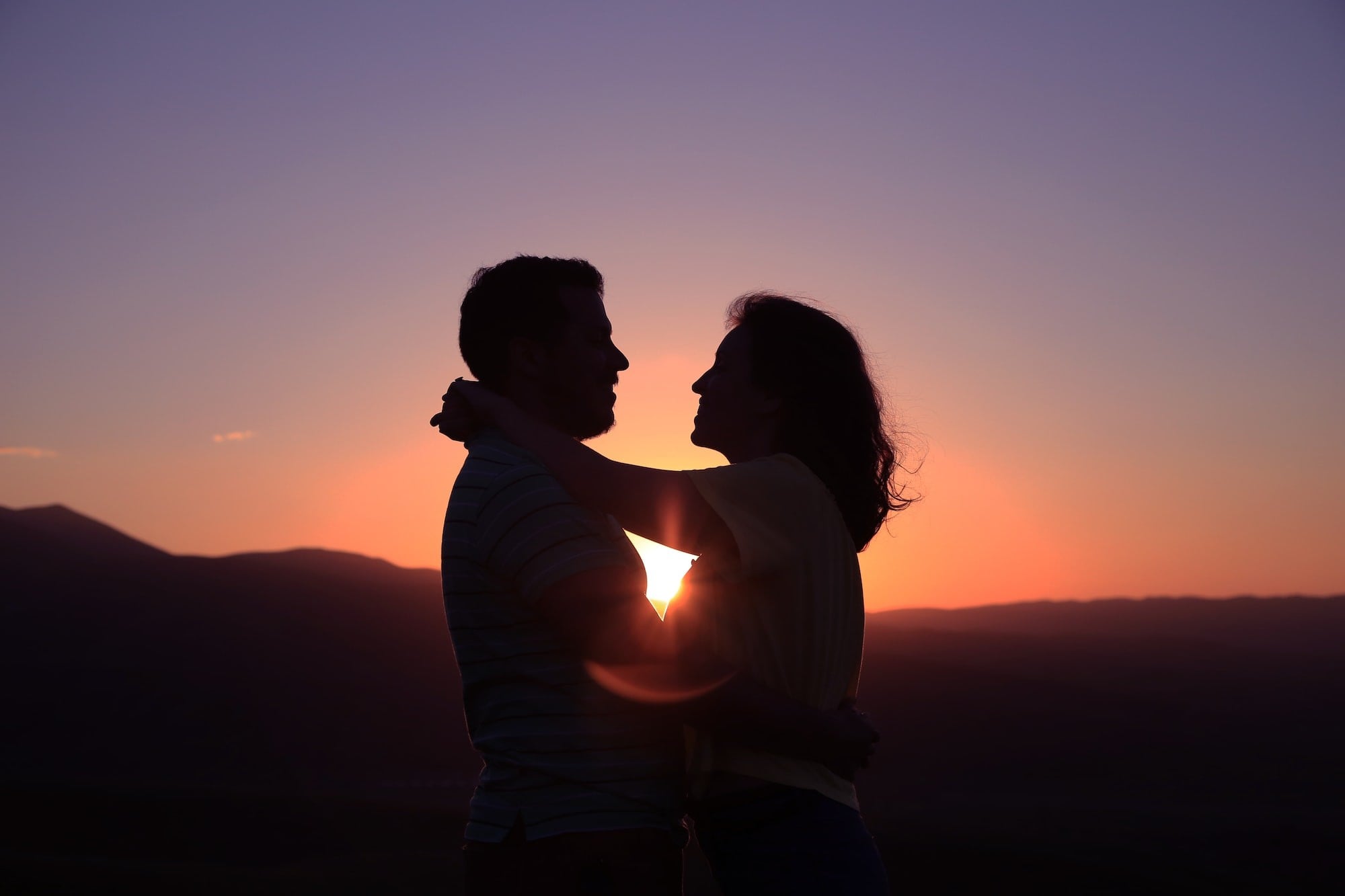 Image of a couple holding each other in the sunset. Image links to webpage describing relationship challenges, attachment styles, and counseling services.