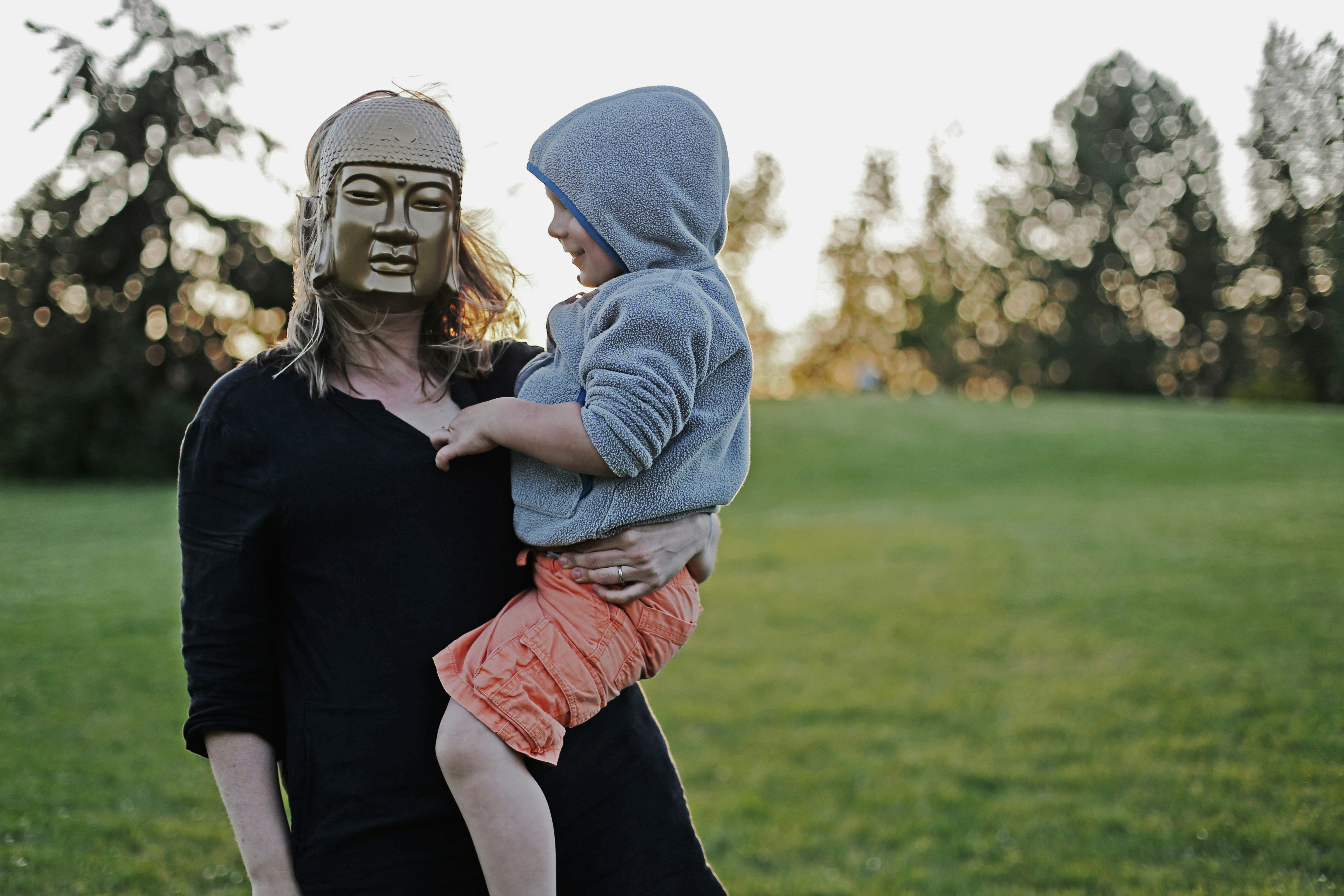 Photo of mother wearing a golden mask while holding her child.